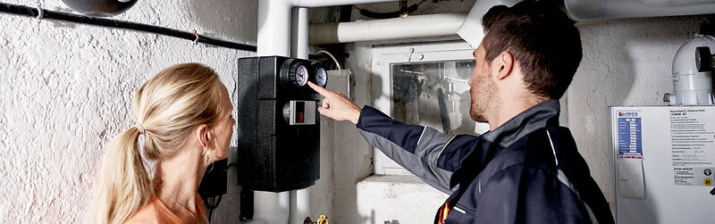 Eine Frau und ein Mann stehen im Keller vor einem Zähler.