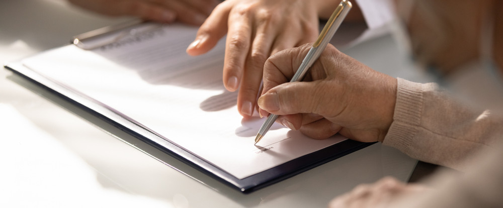 Eine Person unterschreibt gerade ein Formular